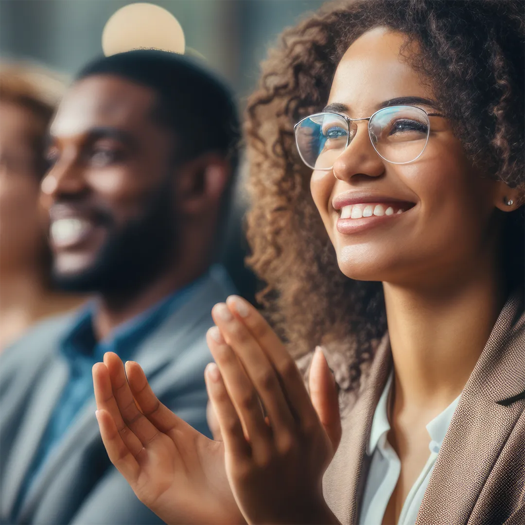 Group of people clapping enthusiastically in an auditorium.