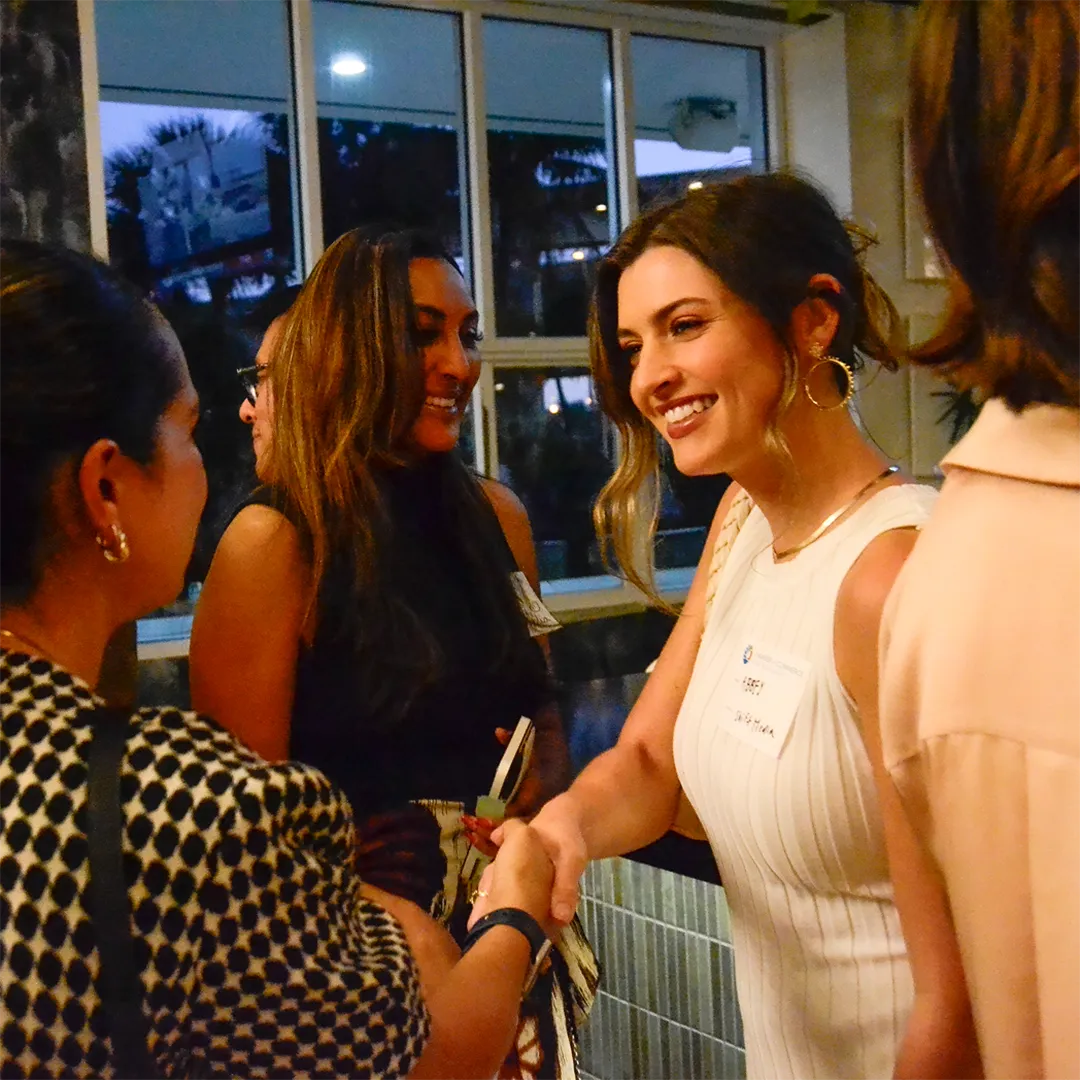 Several women exchanging handshakes at an event.